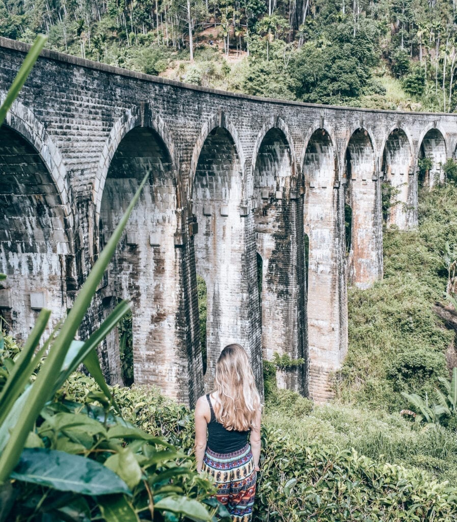 Girl Standing looking up at the Nine Arch bridge in Ella Sri Lanka. 