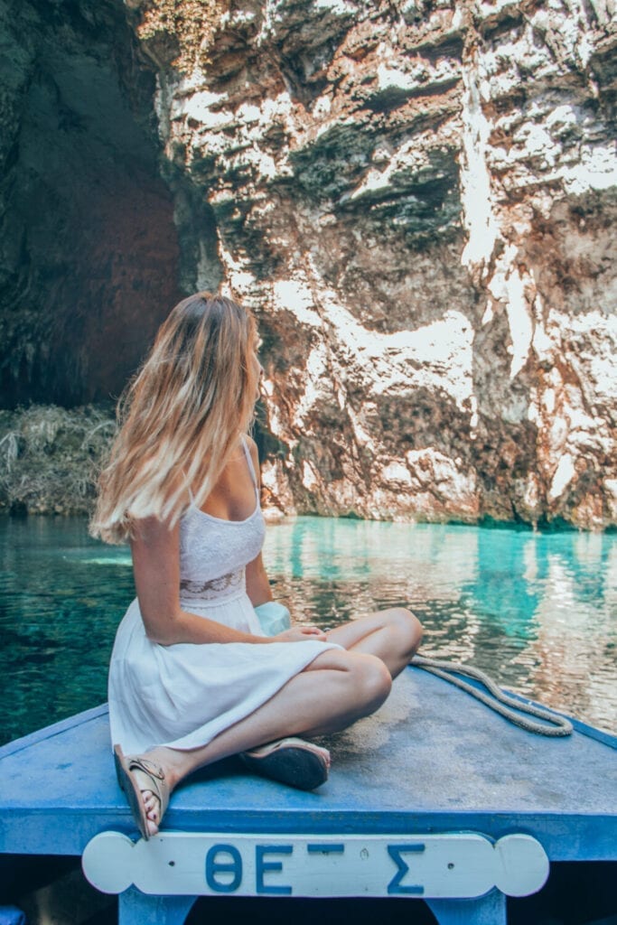 Inside Melissi Cave, bright blue waters on a blue boat.